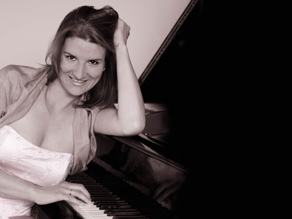 Pianistin Barbara Scherbel (geb. Zenk) am Klavier (Tasten sichtbar), lachend